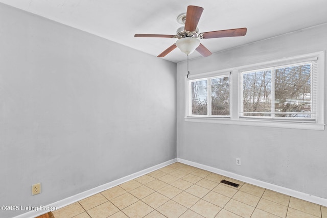 empty room with ceiling fan, light tile patterned flooring, and plenty of natural light