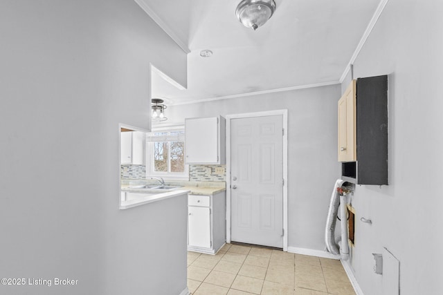 kitchen featuring light tile patterned floors, tasteful backsplash, white cabinetry, ornamental molding, and sink