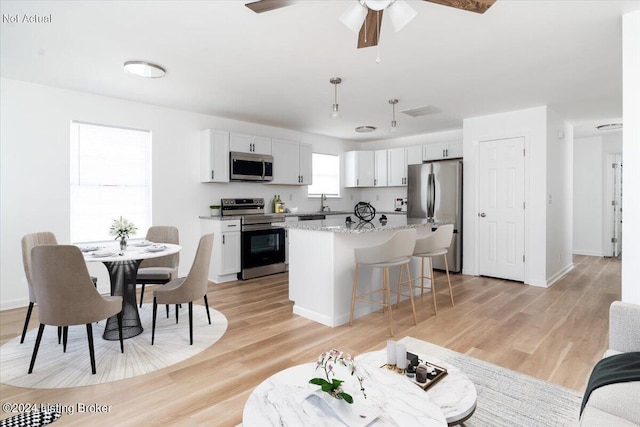 kitchen featuring pendant lighting, a kitchen island, white cabinetry, and stainless steel appliances