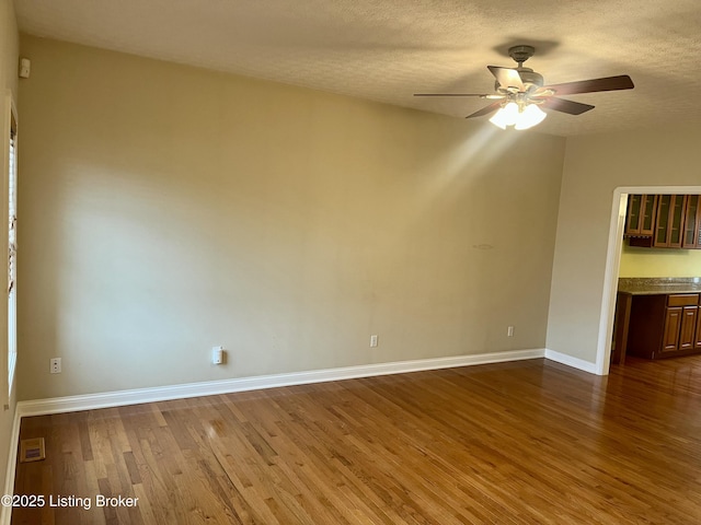 empty room featuring ceiling fan, a textured ceiling, and hardwood / wood-style flooring