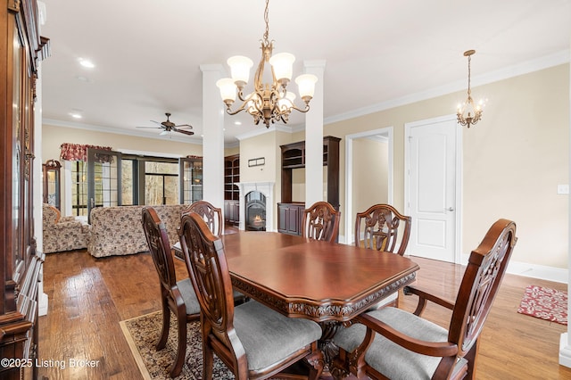 dining space with ceiling fan with notable chandelier, crown molding, and light hardwood / wood-style flooring