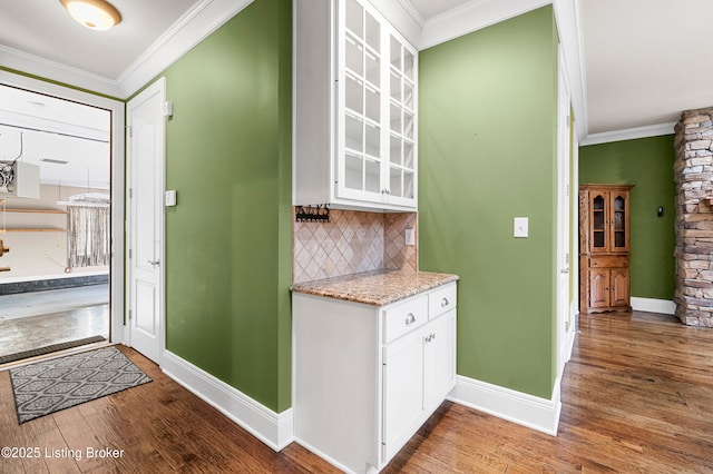 kitchen with crown molding, white cabinetry, backsplash, and dark wood-type flooring