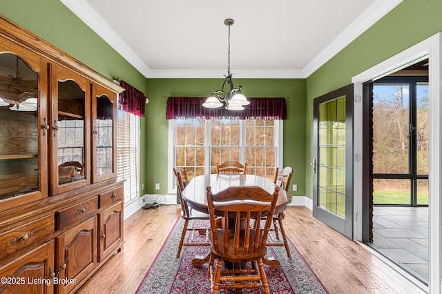 dining room with a chandelier, crown molding, and light hardwood / wood-style floors