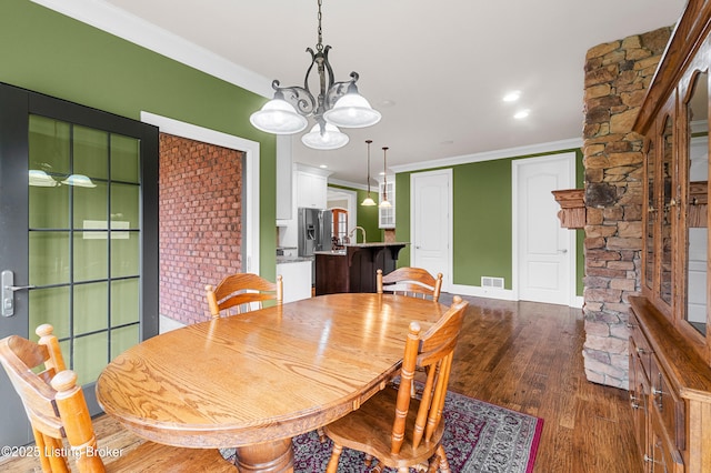 dining space with a chandelier, crown molding, and dark wood-type flooring