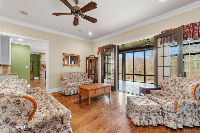 living room with hardwood / wood-style flooring, ceiling fan, and ornamental molding