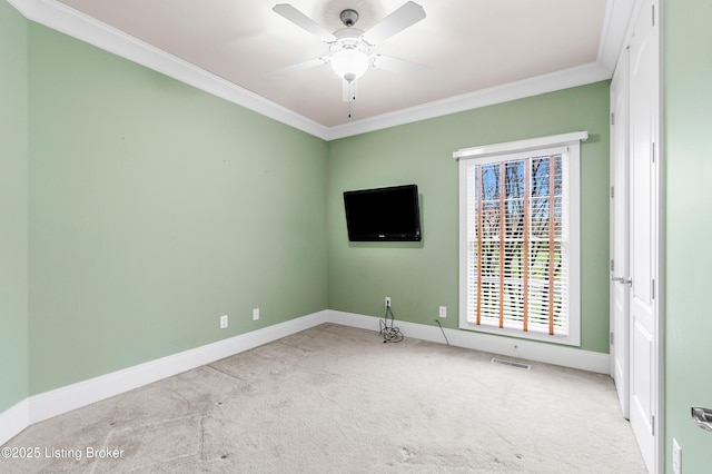 spare room with ceiling fan, ornamental molding, and light carpet