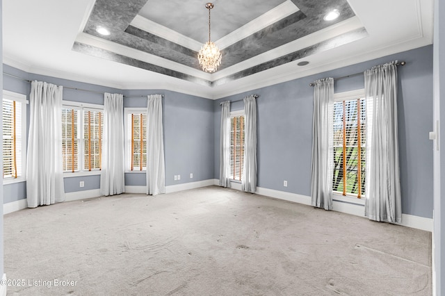 carpeted empty room with a raised ceiling, crown molding, and an inviting chandelier