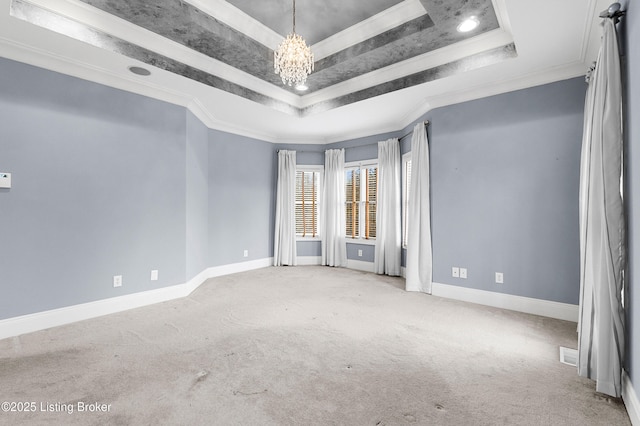 spare room featuring a raised ceiling, crown molding, and carpet