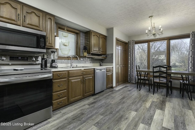 kitchen with sink, stainless steel appliances, a textured ceiling, and a notable chandelier