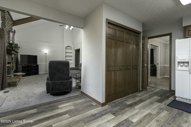 hallway with wood-type flooring, a textured ceiling, lofted ceiling with beams, and built in shelves