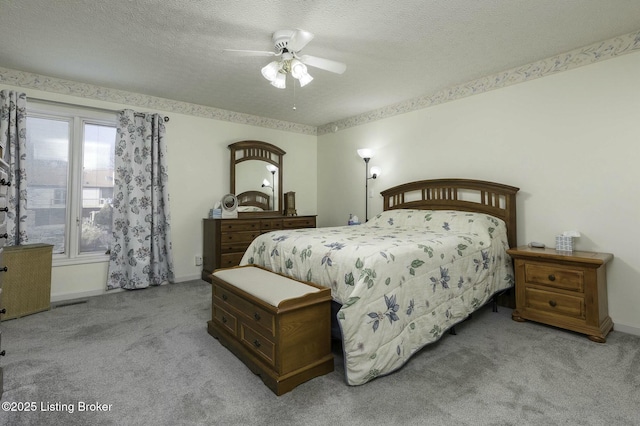 bedroom with a textured ceiling, ceiling fan, and light carpet