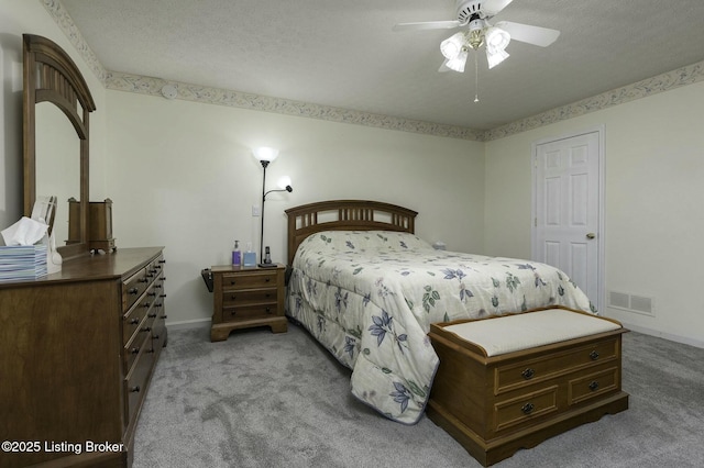 bedroom with a textured ceiling, light colored carpet, and ceiling fan