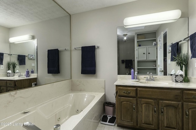 bathroom with tile patterned flooring, vanity, a bath, and a textured ceiling