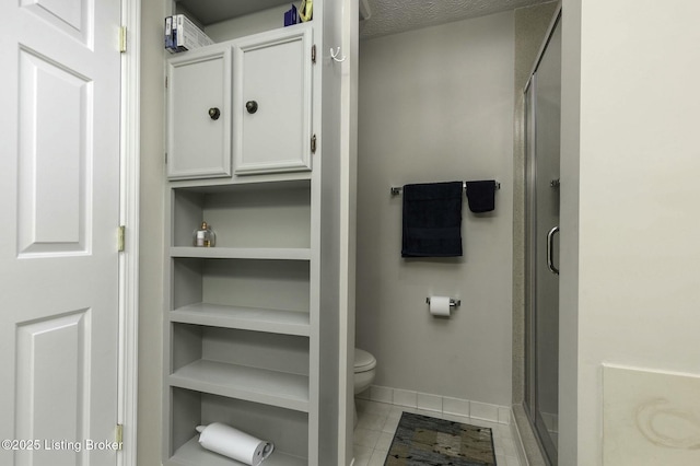 bathroom with tile patterned flooring, a textured ceiling, toilet, and walk in shower