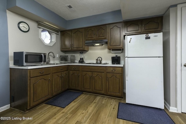 kitchen with light wood-type flooring, dark brown cabinets, a textured ceiling, and stainless steel appliances