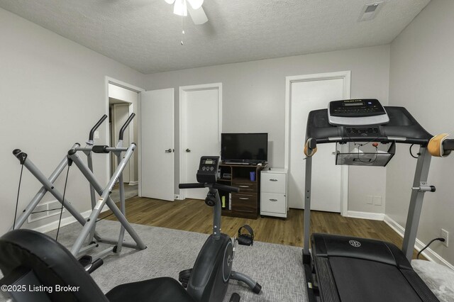 exercise area featuring hardwood / wood-style flooring, ceiling fan, and a textured ceiling