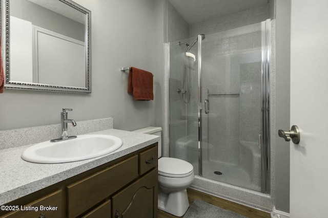 bathroom with hardwood / wood-style flooring, vanity, toilet, and walk in shower