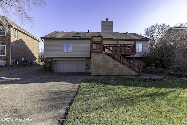 rear view of house featuring a yard, a garage, and a wooden deck