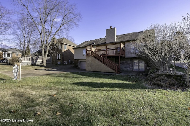 back of property with a yard, a garage, and a deck