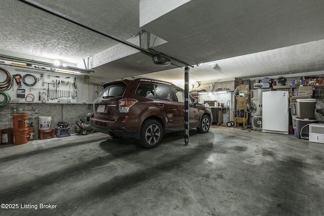 garage featuring a workshop area, white fridge, and a garage door opener