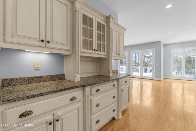 kitchen featuring light hardwood / wood-style flooring, dark stone counters, and french doors