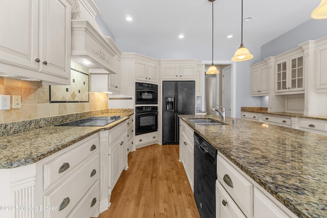 kitchen with white cabinetry, light hardwood / wood-style flooring, dark stone countertops, decorative light fixtures, and black appliances