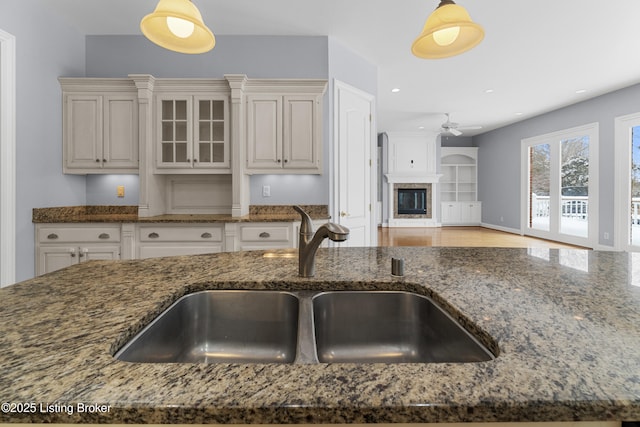 kitchen featuring sink, ceiling fan, dark stone countertops, and hanging light fixtures