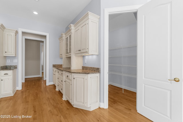 kitchen with white cabinets, dark stone countertops, and light hardwood / wood-style flooring