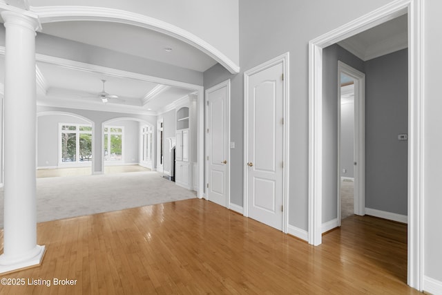 hallway with ornate columns, crown molding, and hardwood / wood-style floors