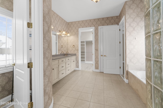 bathroom featuring tile patterned flooring, vanity, and a relaxing tiled tub