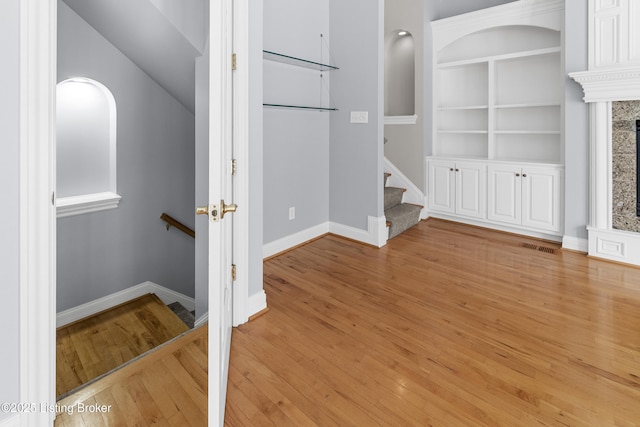 interior space featuring built in shelves, light hardwood / wood-style floors, and a high end fireplace