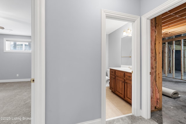 hall with light colored carpet and sink