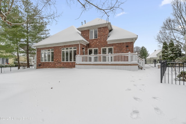 snow covered back of property featuring a wooden deck