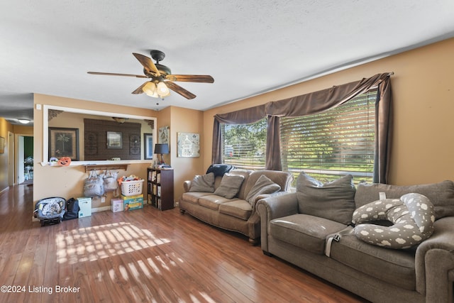 living room featuring ceiling fan, wood-type flooring, and a textured ceiling