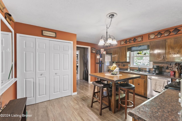 kitchen featuring sink, hanging light fixtures, stainless steel appliances, light hardwood / wood-style floors, and a chandelier