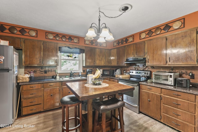 kitchen featuring a chandelier, appliances with stainless steel finishes, light wood-type flooring, and sink