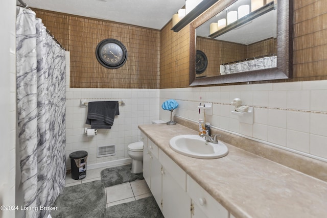 bathroom with curtained shower, tile patterned floors, toilet, vanity, and tile walls