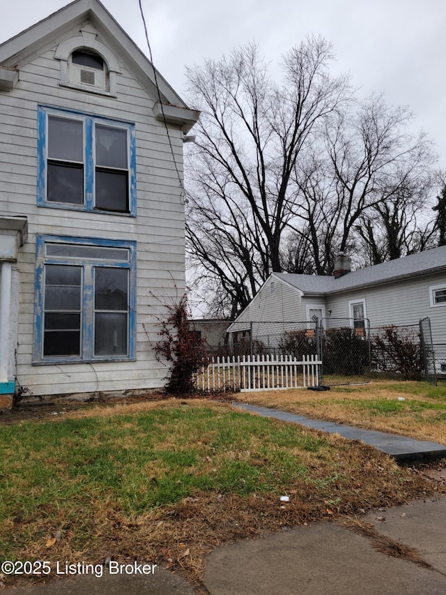 view of side of home with a lawn and fence