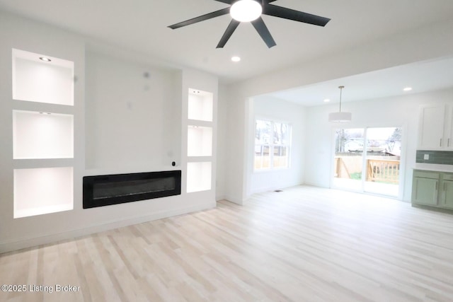 unfurnished living room featuring ceiling fan and light wood-type flooring