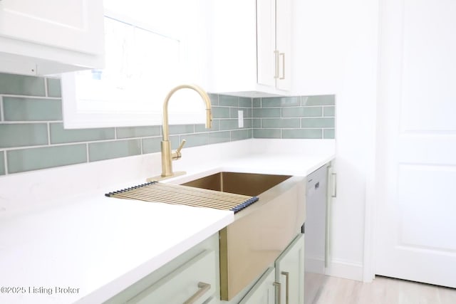 kitchen featuring white cabinets, white dishwasher, sink, tasteful backsplash, and light hardwood / wood-style floors