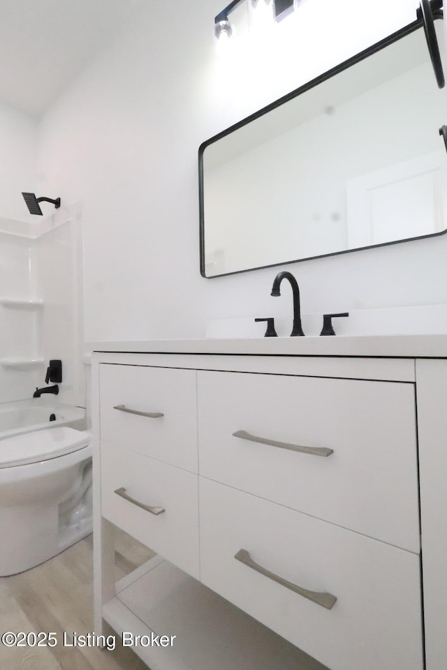 full bathroom with hardwood / wood-style flooring, vanity, toilet, and tub / shower combination