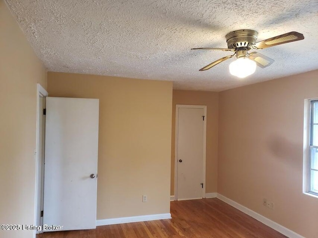 empty room with ceiling fan, a healthy amount of sunlight, wood-type flooring, and a textured ceiling