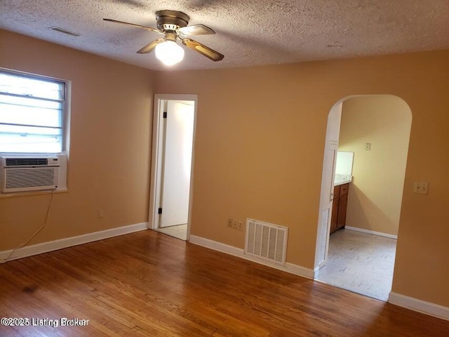 unfurnished room featuring hardwood / wood-style floors, a textured ceiling, cooling unit, and ceiling fan