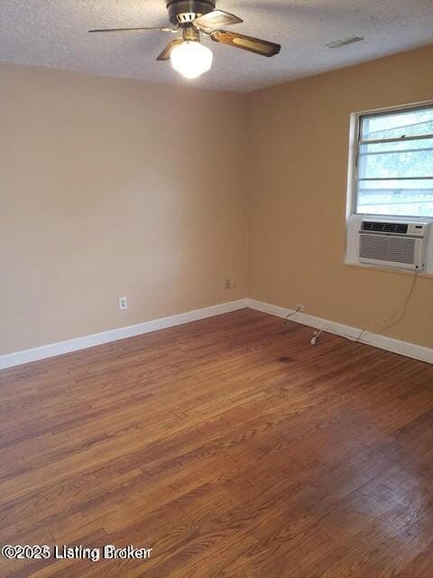 unfurnished room featuring ceiling fan, cooling unit, wood-type flooring, and a textured ceiling