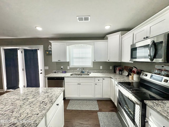 kitchen with light stone countertops, stainless steel appliances, and white cabinetry