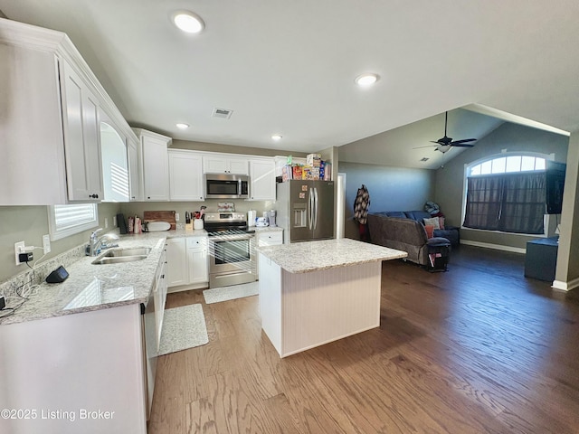 kitchen featuring appliances with stainless steel finishes, white cabinetry, a kitchen island, and sink