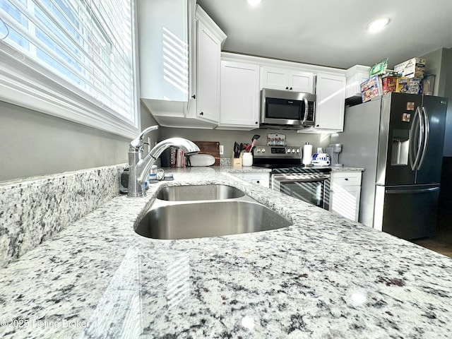 kitchen with white cabinetry, sink, stainless steel appliances, and light stone counters