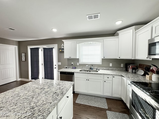 kitchen featuring dark wood-type flooring, sink, light stone countertops, appliances with stainless steel finishes, and white cabinetry