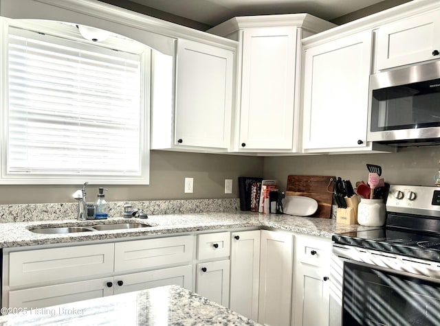 kitchen featuring white cabinets, sink, light stone countertops, and stainless steel appliances