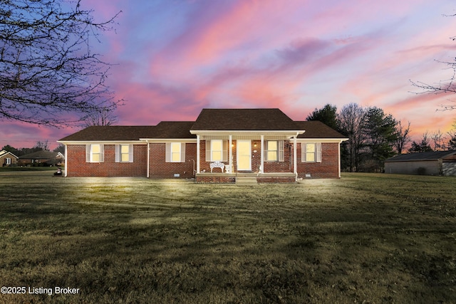 ranch-style house featuring covered porch and a yard